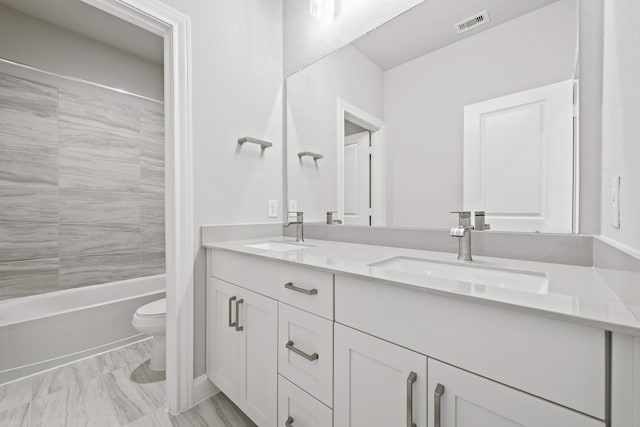 full bathroom featuring toilet, double vanity, tub / shower combination, and a sink