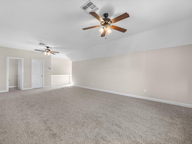 carpeted empty room with a ceiling fan, visible vents, vaulted ceiling, and baseboards