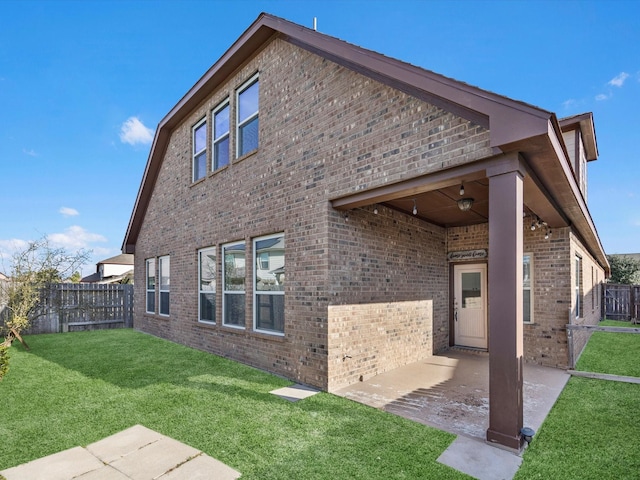 back of property with a patio area, brick siding, a yard, and a fenced backyard