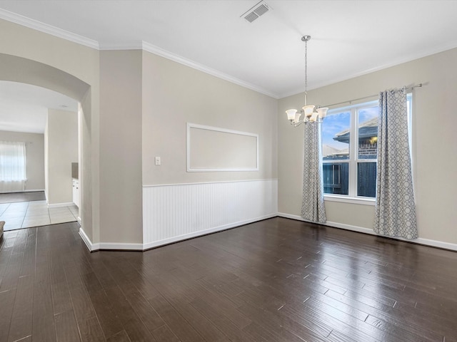 empty room featuring crown molding, visible vents, arched walkways, and wood finished floors