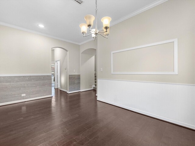 spare room featuring arched walkways, a wainscoted wall, an inviting chandelier, and wood finished floors