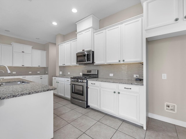 kitchen with appliances with stainless steel finishes, stone counters, white cabinetry, and a sink