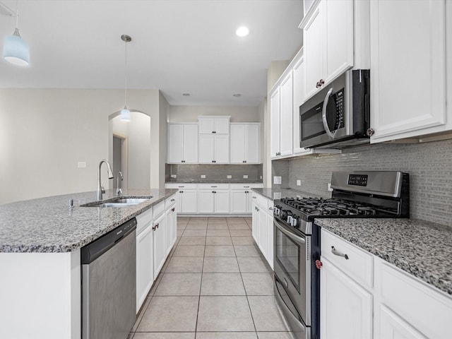 kitchen featuring light stone counters, light tile patterned floors, backsplash, appliances with stainless steel finishes, and a sink