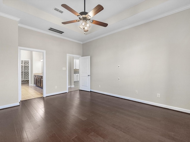 spare room with dark wood-type flooring, visible vents, ceiling fan, and baseboards