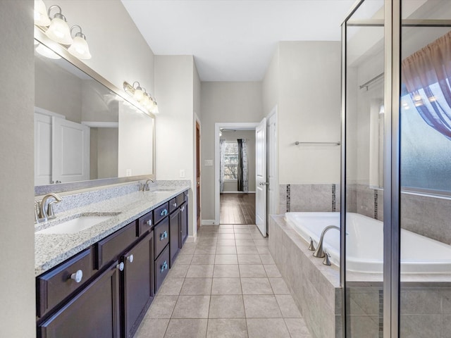 full bathroom featuring a bath, double vanity, a sink, and tile patterned floors