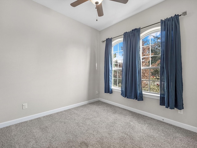 carpeted spare room with baseboards and a ceiling fan