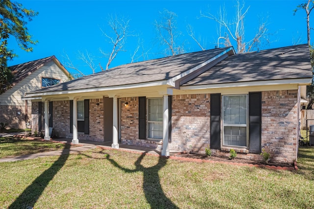 ranch-style home with a porch, brick siding, a front lawn, and roof with shingles