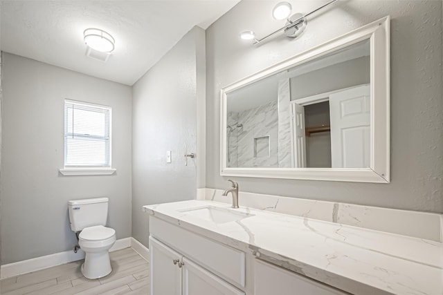 bathroom featuring toilet, wood finished floors, vanity, baseboards, and walk in shower