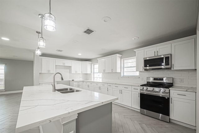 kitchen with light stone countertops, decorative backsplash, stainless steel appliances, and a sink