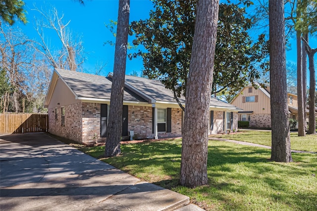 view of front of house with a front yard, brick siding, and fence