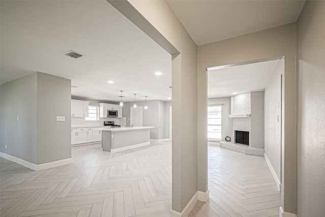 hallway with recessed lighting, visible vents, a sink, and baseboards