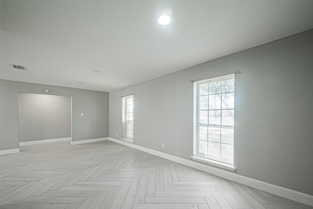 empty room with a wealth of natural light, visible vents, and baseboards