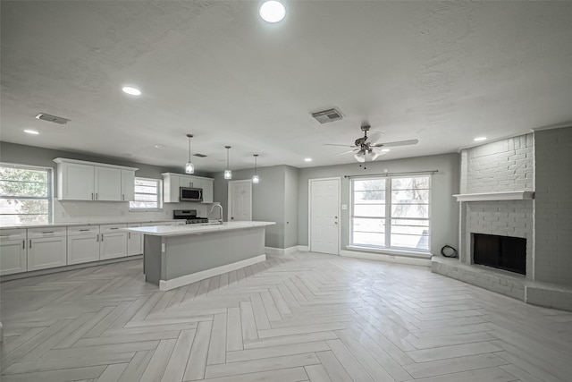 kitchen featuring open floor plan, stainless steel appliances, a textured ceiling, and visible vents