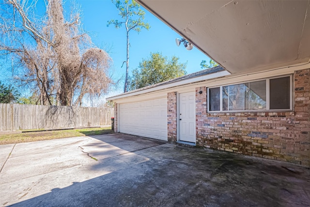 garage featuring concrete driveway and fence