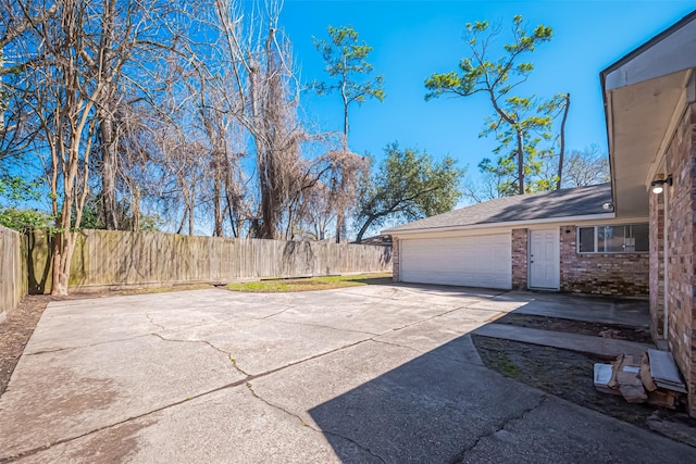 view of patio / terrace with driveway, an attached garage, and fence