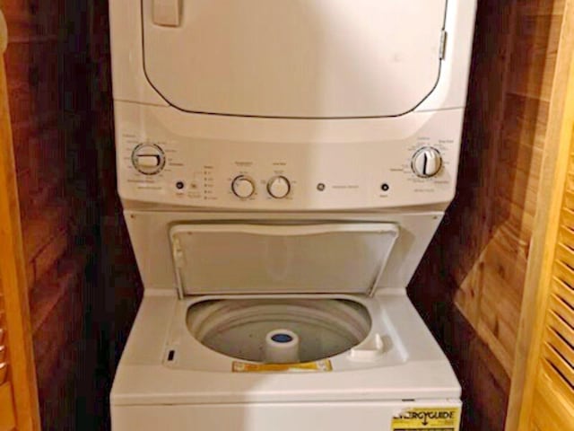 clothes washing area featuring laundry area and stacked washing maching and dryer