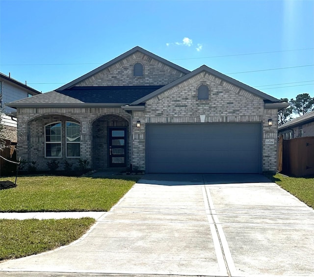 french provincial home featuring a garage, brick siding, driveway, and a front lawn