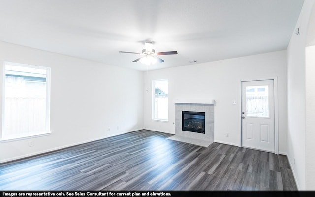 unfurnished living room with dark wood finished floors, visible vents, ceiling fan, a tile fireplace, and baseboards