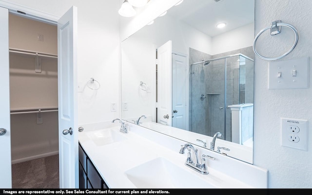 bathroom featuring a shower stall, a spacious closet, and a sink