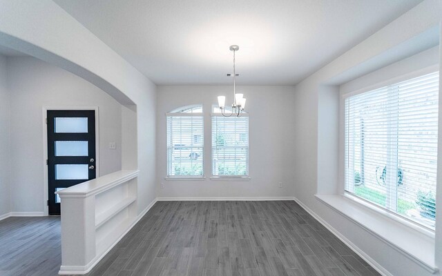 13709 Seneca Lake Dr, Texas City, TX 77568 - unfurnished dining area with dark wood-style floors, a chandelier, baseboards, and arched walkways