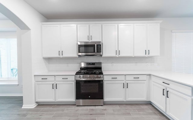 13709 Seneca Lake Dr, Texas City, TX 77568 - kitchen featuring appliances with stainless steel finishes, arched walkways, tasteful backsplash, and white cabinetry