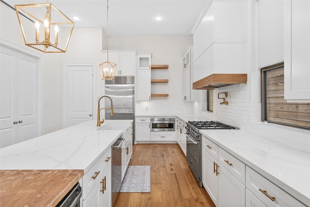 kitchen featuring open shelves, light wood-style flooring, decorative backsplash, white cabinetry, and high quality appliances