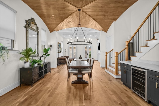 dining area featuring beverage cooler, light wood-type flooring, wooden ceiling, and stairs