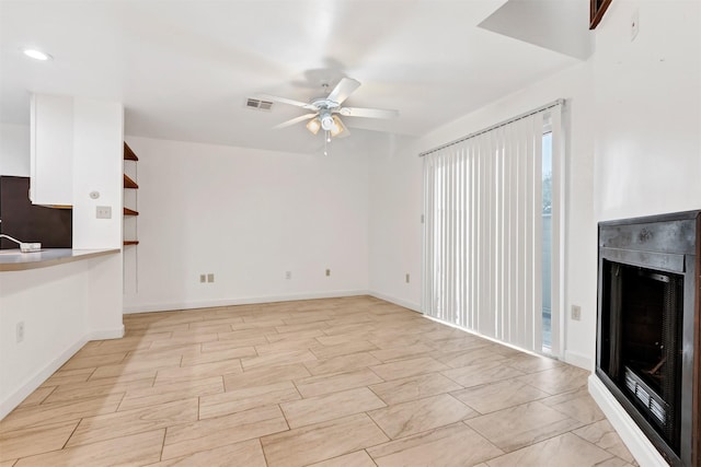 unfurnished living room featuring ceiling fan, visible vents, and baseboards