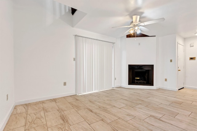 unfurnished living room with ceiling fan, a fireplace, and baseboards