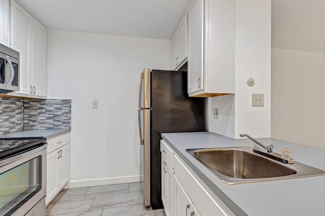 kitchen featuring stainless steel appliances, white cabinetry, a sink, and tasteful backsplash