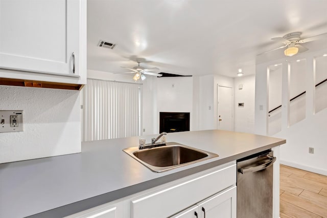 kitchen featuring a sink, visible vents, white cabinetry, light wood-type flooring, and dishwasher