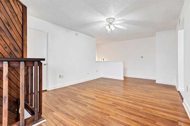 spare room with light wood finished floors, ceiling fan, baseboards, and a textured ceiling