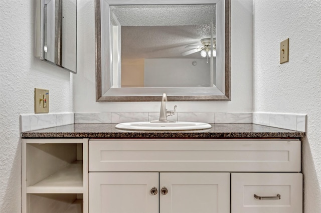 bathroom featuring a ceiling fan, a textured wall, a textured ceiling, and vanity