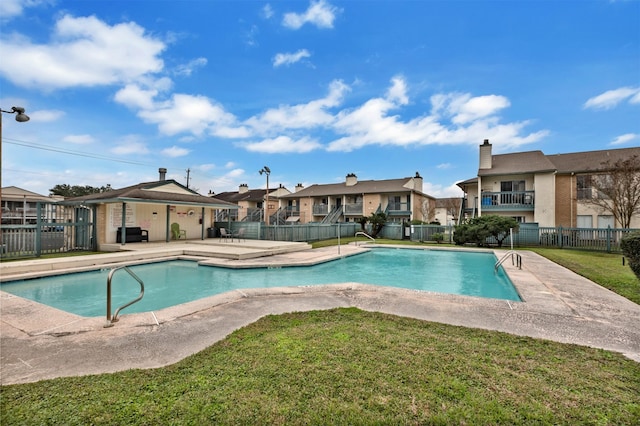 pool with a patio area, a residential view, fence, and a yard