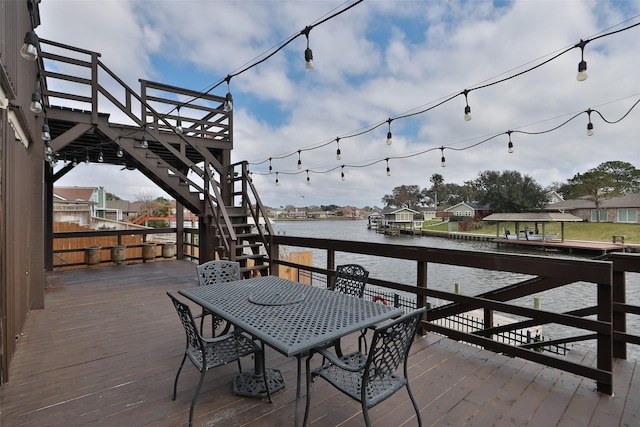 wooden deck with a water view, stairs, a residential view, and outdoor dining area