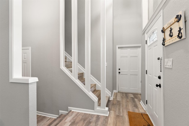 foyer entrance featuring stairway, wood finished floors, and baseboards