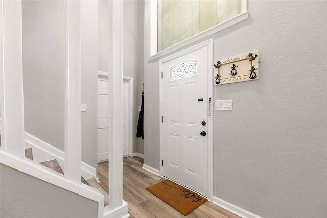 foyer with a textured wall, baseboards, and wood finished floors