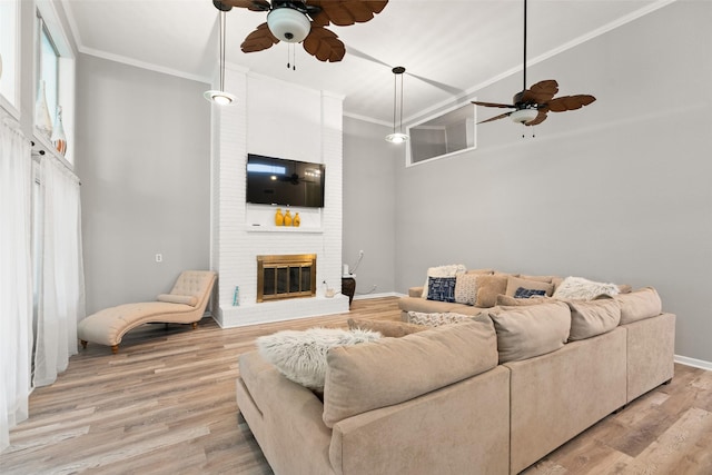 living area with light wood finished floors, a fireplace, and ornamental molding