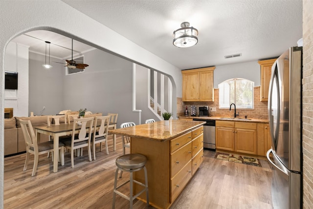 kitchen featuring arched walkways, visible vents, appliances with stainless steel finishes, light wood-style floors, and a sink