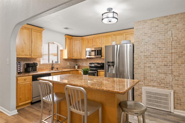 kitchen with a breakfast bar, visible vents, appliances with stainless steel finishes, a sink, and wood finished floors