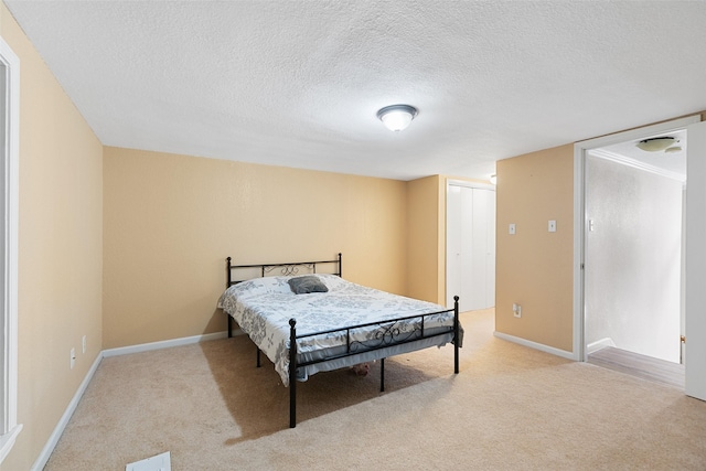 bedroom featuring light carpet, baseboards, and a textured ceiling