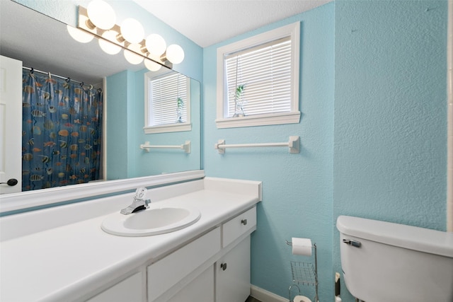 bathroom with toilet, a textured wall, a shower with shower curtain, and vanity