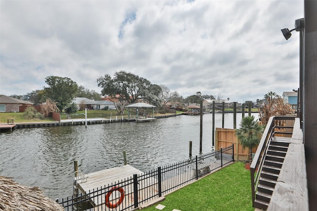 property view of water featuring a dock, fence, and a residential view