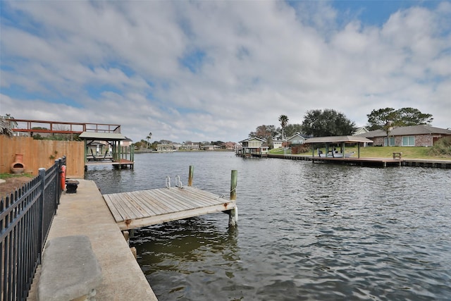 view of dock with a water view and fence