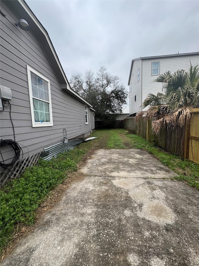 view of side of home with a lawn, a patio area, and fence