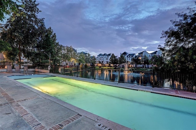 view of swimming pool featuring a residential view, a water view, and fence