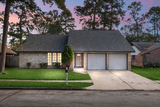 view of front of home with a front yard, concrete driveway, roof with shingles, and an attached garage