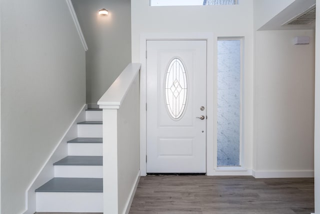 foyer entrance with visible vents, stairway, baseboards, and wood finished floors