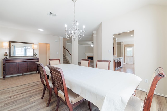 dining room with a healthy amount of sunlight, decorative columns, and light wood-style flooring