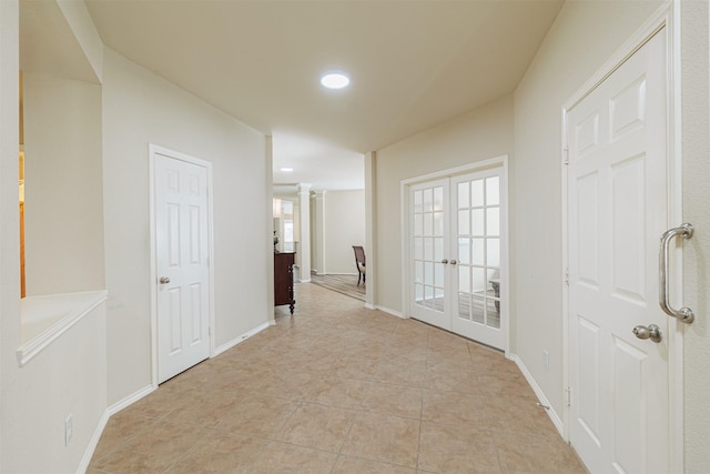 hallway with light tile patterned floors, baseboards, french doors, ornate columns, and recessed lighting